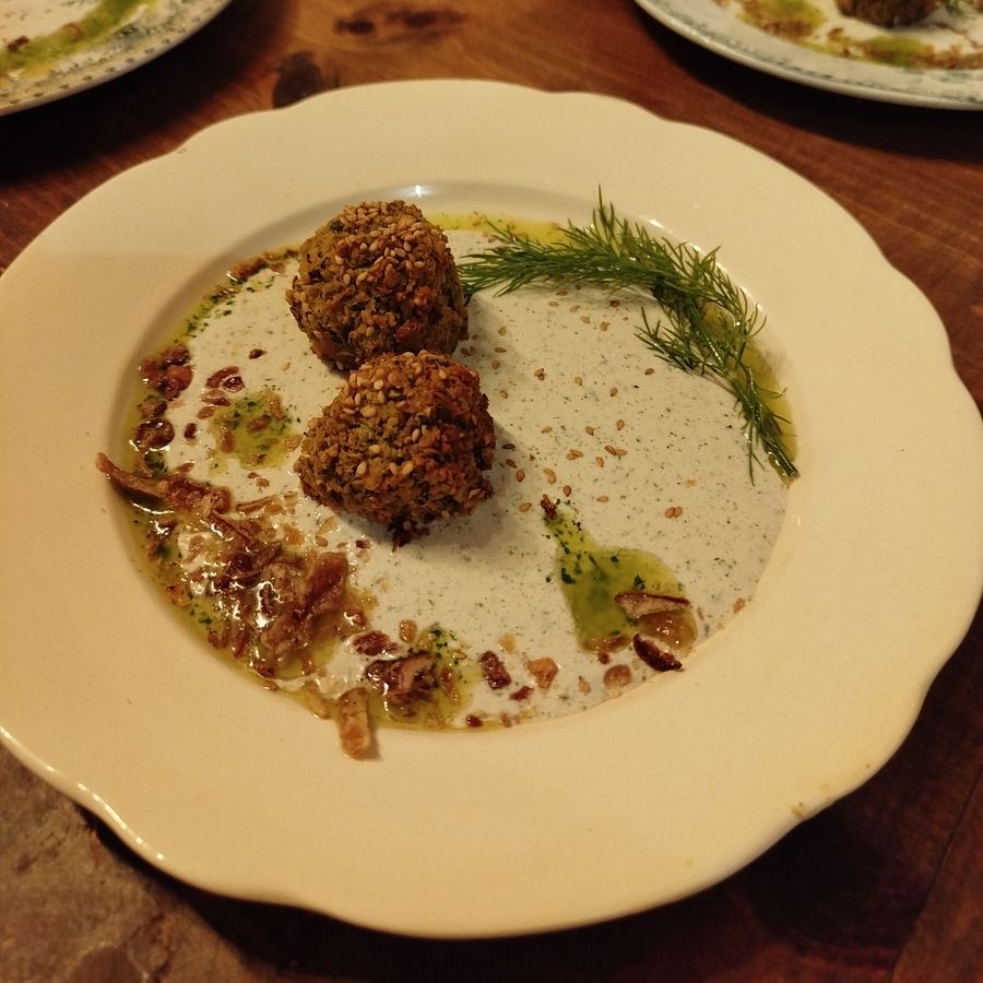 Boulettes végétales aux graines sur une crème, avec une huile d'herbes et de l'aneth.