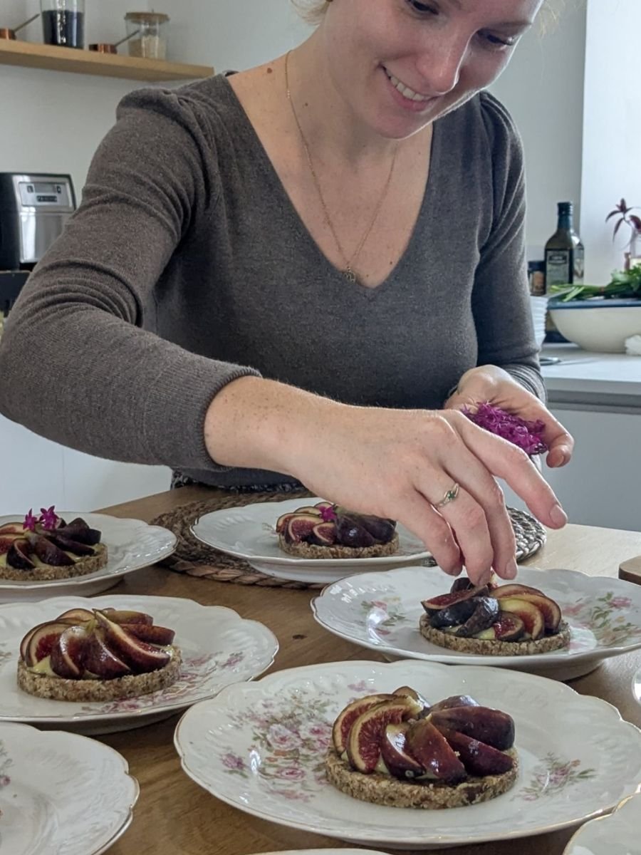 Laura Bridier dressant des tartelettes aux figues sur des assiettes de porcelaine fleurie.
